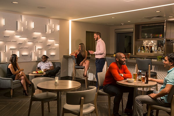 A Marriott hotel bar and sitting area with tables and chairs features commercial lighting design by Arkansas Lighting on the walls and ceiling.